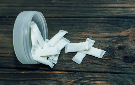 Round container of nicotine pouches spilling onto table