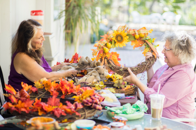 Older woman at craft show booth buying wreath of fall flowers from seller