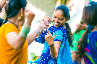 East Indian woman in blue sari dancing with other East Indian women